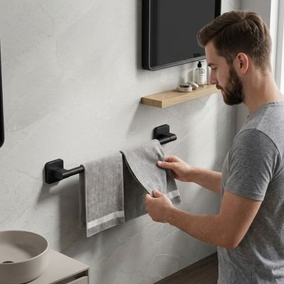 homme place deux serviettes sur porte serviette fixe au mur a cote lavabo